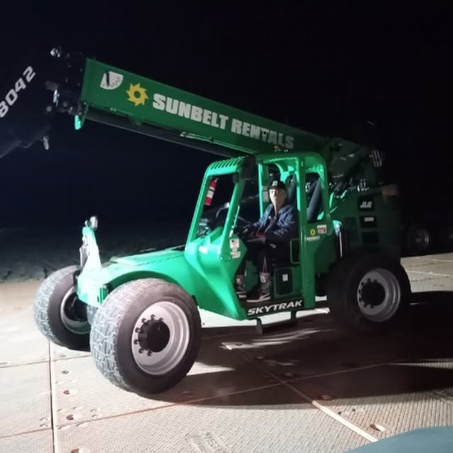 Team member operating a telehandler at night